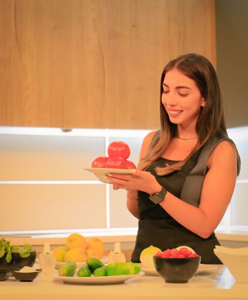 Nour, registered dietitian-nutritionist, holding a plate of fresh tomatoes in a studio kitchen
